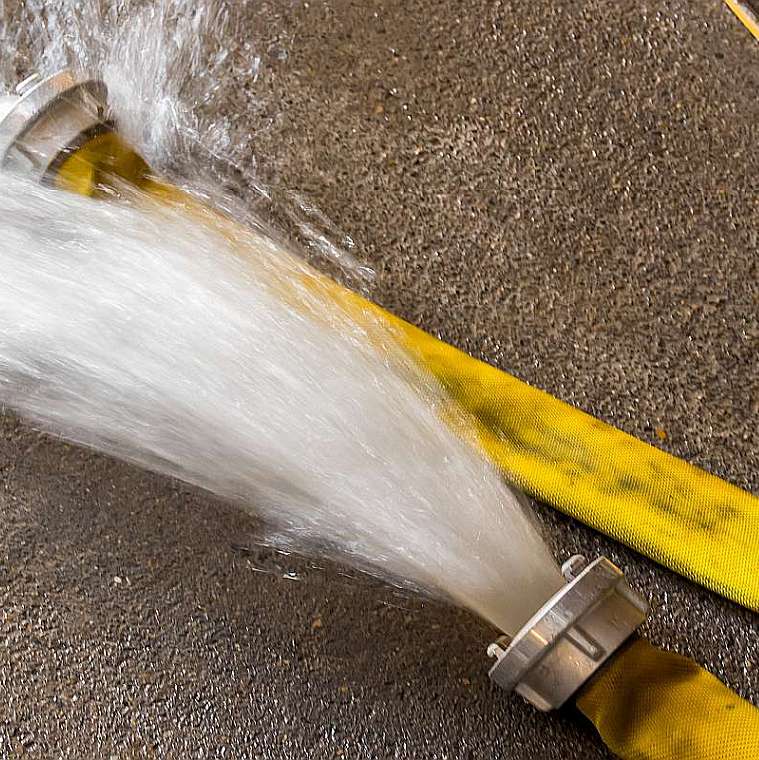 Über eine gelben Feuerwehrschlauch wird nach einem Starkregen das Wasser aus der Hotelhalle gepumpt.